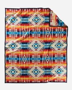 Pendleton wool blanket, with geometric shape patterns in ivory, reds, oranges, and blues, named Pilot Rock.